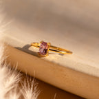 Blush Pink Emerald Ring with a rectangular blush pink gemstone set in gold, shown on a neutral background with soft, warm lighting.