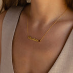 The Mellow Name Heart Birthstone Necklace featuring "Charlotte" sits elegantly on a woman's neck, beautifully complementing her beige v-neck top—a perfect choice for Minimalist Jewelry enthusiasts.