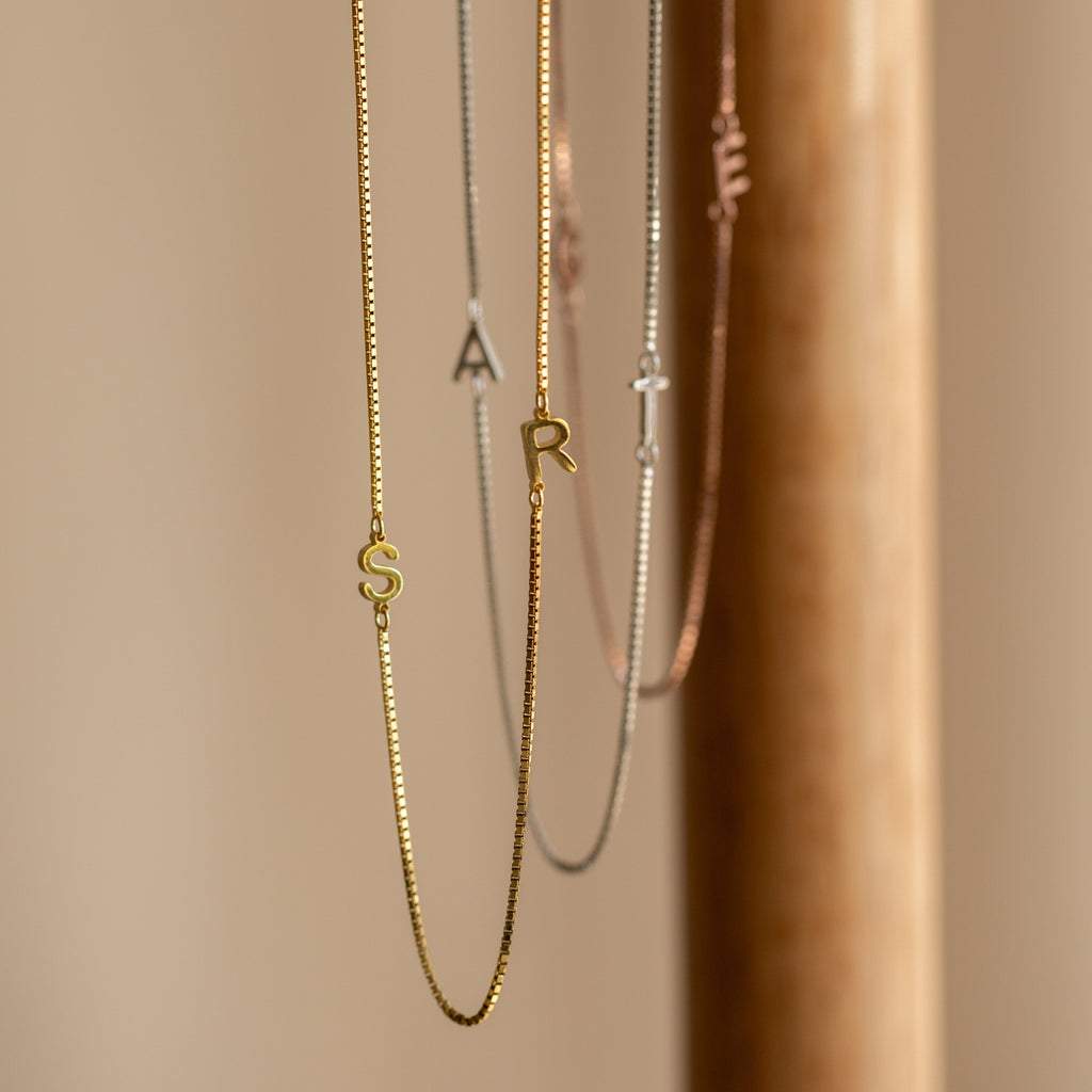 Gold and silver Duo Initial Necklace in Box Chain featuring S, A, and R letter charms, elegantly displayed on a neutral background. Personalize your style with this perfect accessory.