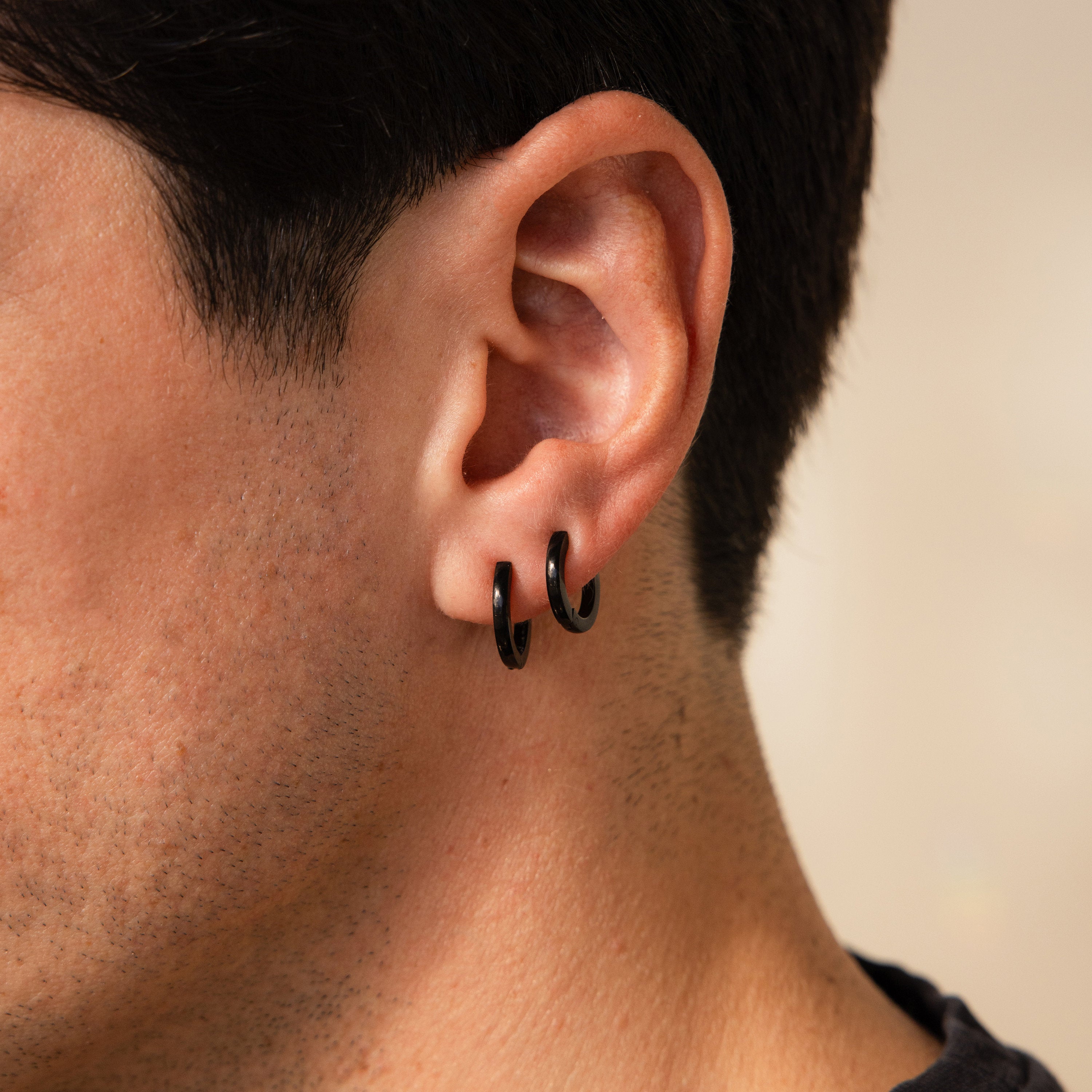 Close-up of a person's ear wearing the Men's Black Hoops Set, highlighting these stylish men's earrings.
