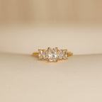 The Art Deco Birthstone Ring features a central rectangular diamond accented by baguette-cut stones on each side, exuding vintage elegance.