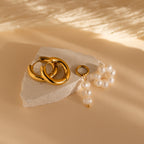 Mismatched Pearl Drop Hoops are displayed on white stone with a beige background.