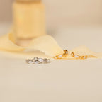 Two pairs of Marquise Inlay Huggies—one silver, one gold—are displayed on soft cream fabric.