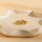 A pair of Baguette Link Hoops rests elegantly on a white plate, highlighting the timeless charm of minimalist geometric gold earrings.
