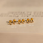 Three pairs of Diamond Flatback Studs Set in 18K Gold, in large, medium, and small sizes, are beautifully displayed on a beige surface.