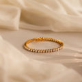 The Bold Diamond Tennis Bracelet, featuring sparkling diamonds, rests on soft beige fabric in gentle natural light—a stylish choice for bridesmaid jewelry or any special occasion.