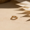 The Inside Out Huggies Set features gold hoop earrings with small clear gemstones that sparkle on a beige surface in soft, natural light, adding a subtle and refined touch to any look.
