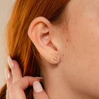 Close-up of a woman’s ear wearing Pink Baguette Opal Studs, ideal as bridal gifts, with her hand resting near her ear.