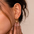Close-up of a woman's ear wearing the Opal Starburst Earrings Set, with her hand touching her face to show nude manicured nails.