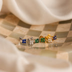 The Flower Flat Back Studs Set features five pairs of colorful floral stud earrings arranged on a checkered surface with a soft fabric backdrop, highlighting trendy earrings ideal for everyday wear.