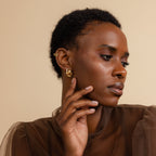  Model wearing gold Mini Triple Knot Earrings, with a pave earring, gold stud and gold cuff, shown in a styled portrait.