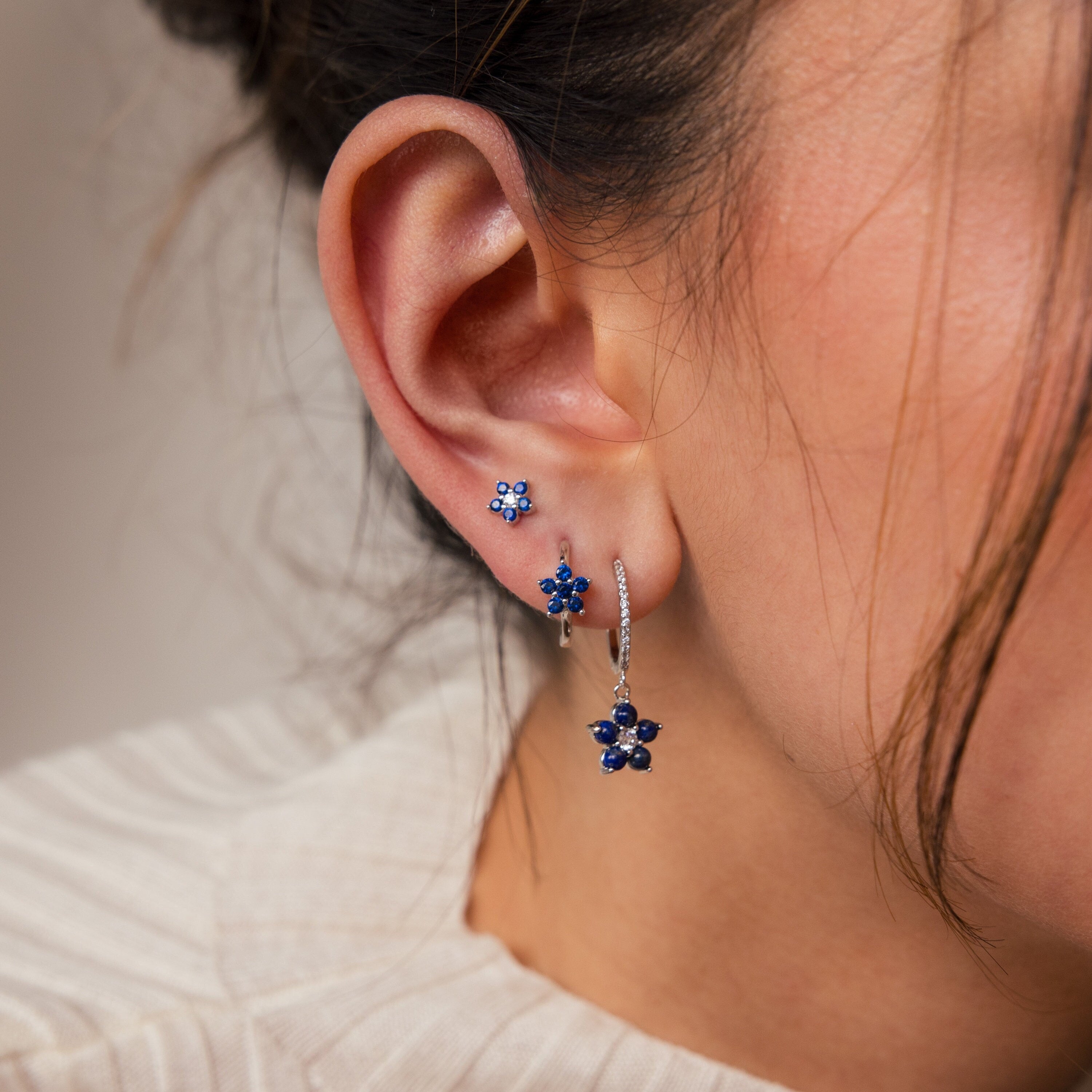 Close-up of a woman's ear wearing the Sapphire Flower Earrings Set - Silver with a cream textured top—an elegant accessory, perfect as an anniversary gift.