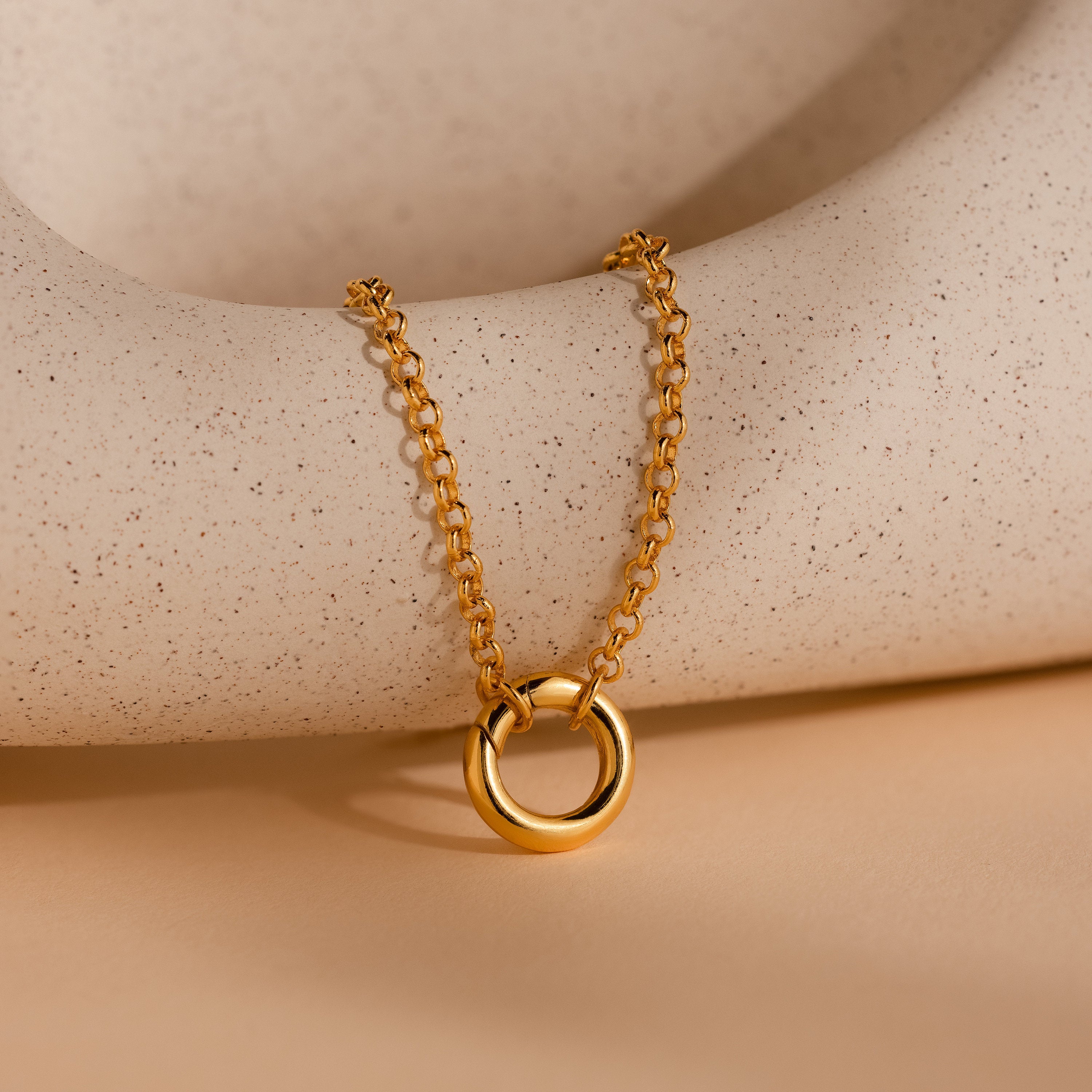 Rolo Circle Charm Bracelet with a detachable hinged circle pendant, shown on a neutral speckled background—add your favorite charms for a personalized style.