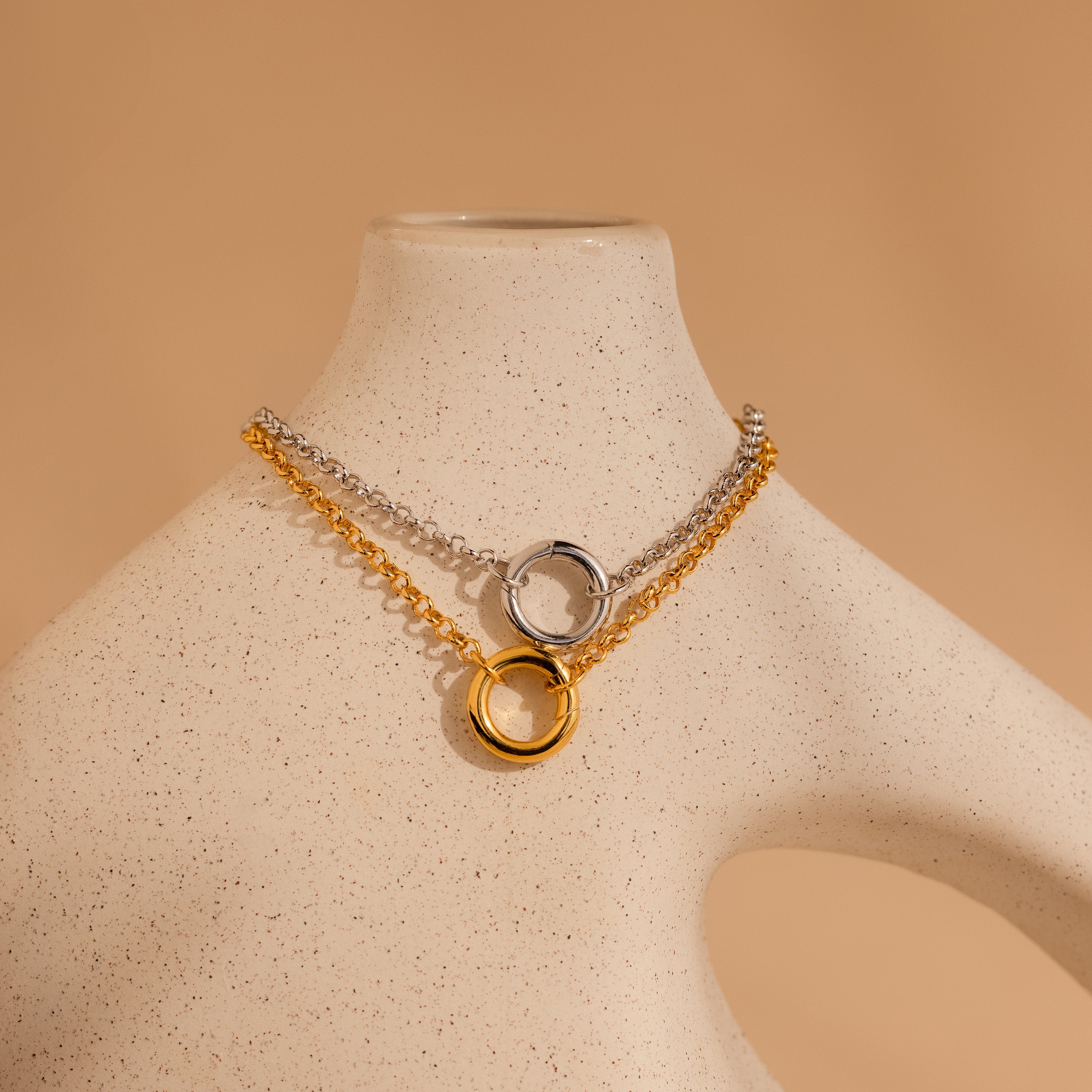 The Rolo Circle Charm Bracelet in 18K Gold is displayed on a speckled beige mannequin bust, featuring a detachable hinged circle pendant—perfect for adding charms and creating your own personalized style.