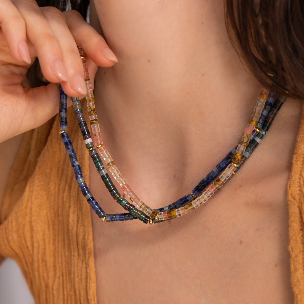 A woman showcases the Tanzanite Beaded Necklace, its vivid blue beads standing out against her brown textured top.