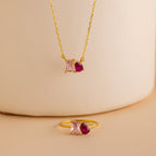 Toi et Moi Birthstone Necklace featuring pink square and red teardrop gemstones on a beige background—ideal for anyone seeking personalized gemstone or custom birthstone jewelry.