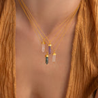 Close-up of three Crystal Quartz Necklaces with hexagonal point pendants, radiating positive energy, worn over a brown textured top.