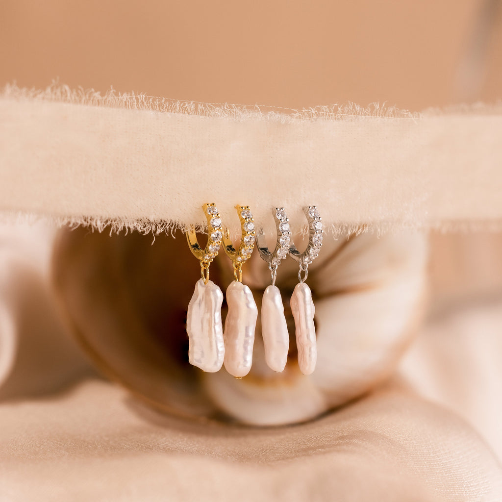 The Baroque Pearl Pave Huggies feature elegant huggie hoops with baroque pearl accents, perfect for adding timeless charm to any jewelry collection.