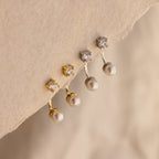 Two pairs of Diamond Pearl Ear Jackets—crafted in gold and silver—showcase sparkling diamonds and pearls, ideal for minimalist jewelry lovers, elegantly displayed on a textured surface.