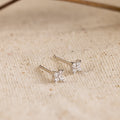 Diamond Ivy Flower Studs feature silver star-shaped designs with small diamonds, presented on a textured beige fabric. Perfect for weddings or adding everyday sparkle, these earrings are a versatile and elegant accessory.