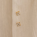 The Diamond Ivy Flower Studs, ideal for weddings or everyday wear, are shown in pairs on a cream-colored textured fabric background.