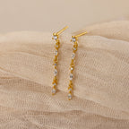 Dainty Diamond Drop Earrings, ideal for weddings or bridesmaids, featuring sparkling crystals and displayed on a soft beige textured fabric background.