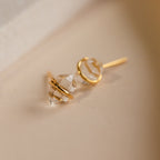 A pair of Herkimer Diamond Earrings featuring gold and clear glass stones resting on a neutral surface.