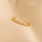The Diamond Station Ring features small round diamonds on a thin gold band, ideal as a promise ring or minimalist engagement ring, shown on a beige background.