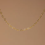 The Heart Link Chain Bracelet features small, repeating heart-shaped links for a romantic look, elegantly displayed against a plain brown background.
