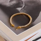 The 3 Prong Tennis Bracelet with clear gemstones rests atop a stack of books, making an elegant statement piece.