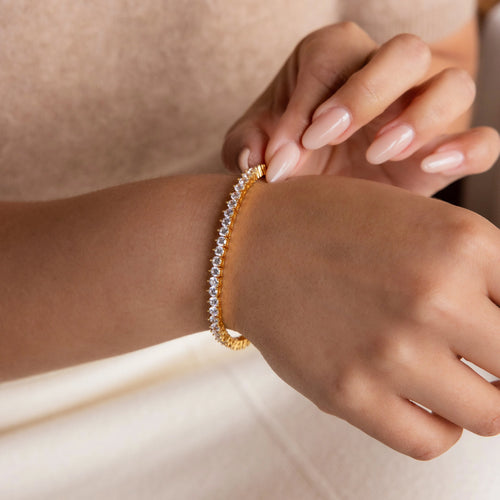 A person adjusts the elegant 3 Prong Tennis Bracelet on their wrist, showcasing its sparkling small diamonds.