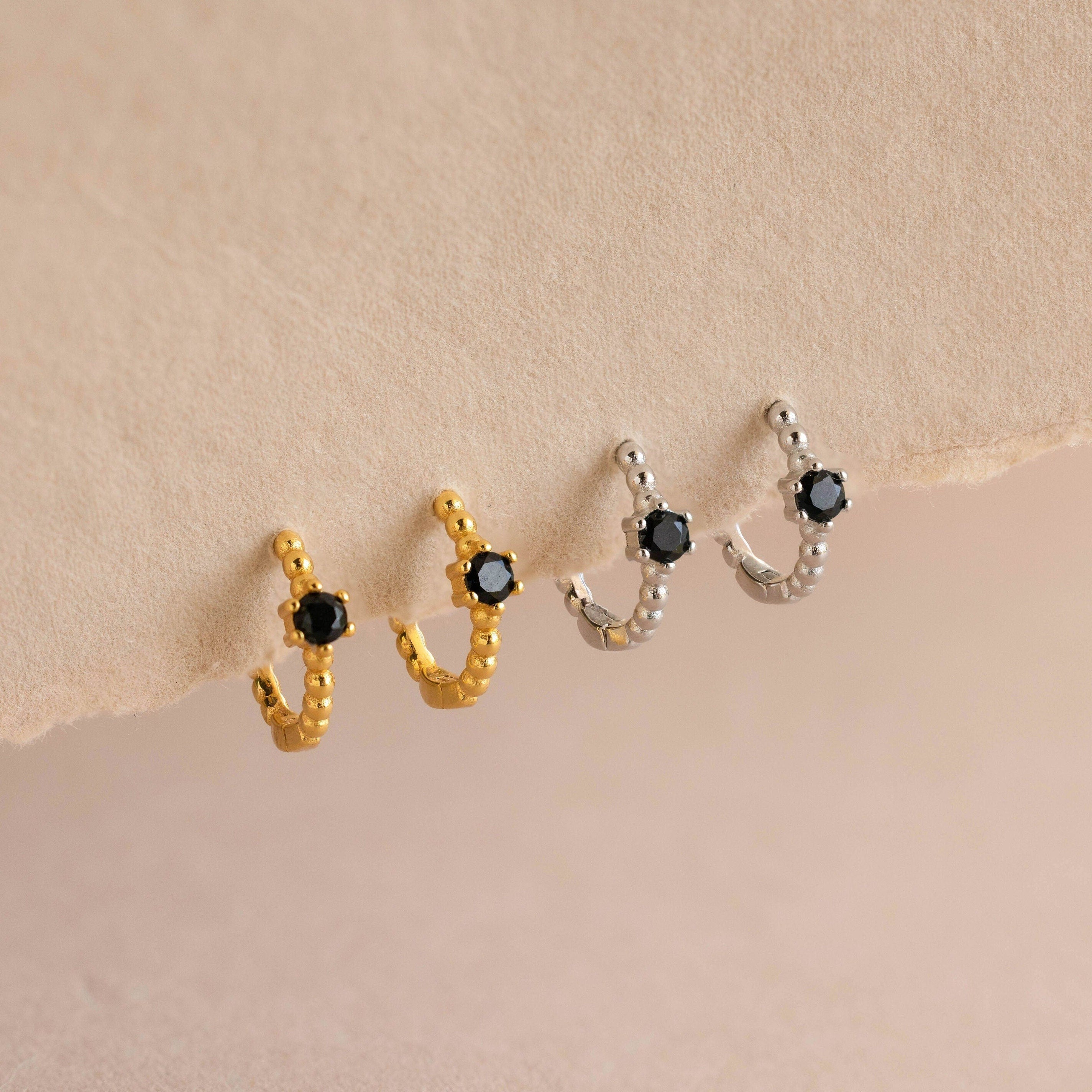 Two pairs of Onyx Beaded Huggies—one gold, one silver—each with a hexagonal Onyx charm for subtle elegance.