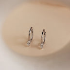 Elegant and timeless, the Pear Diamond Drop Hoops showcase teardrop-shaped crystals on classic silver hoops against a beige background—an ideal wedding accessory.