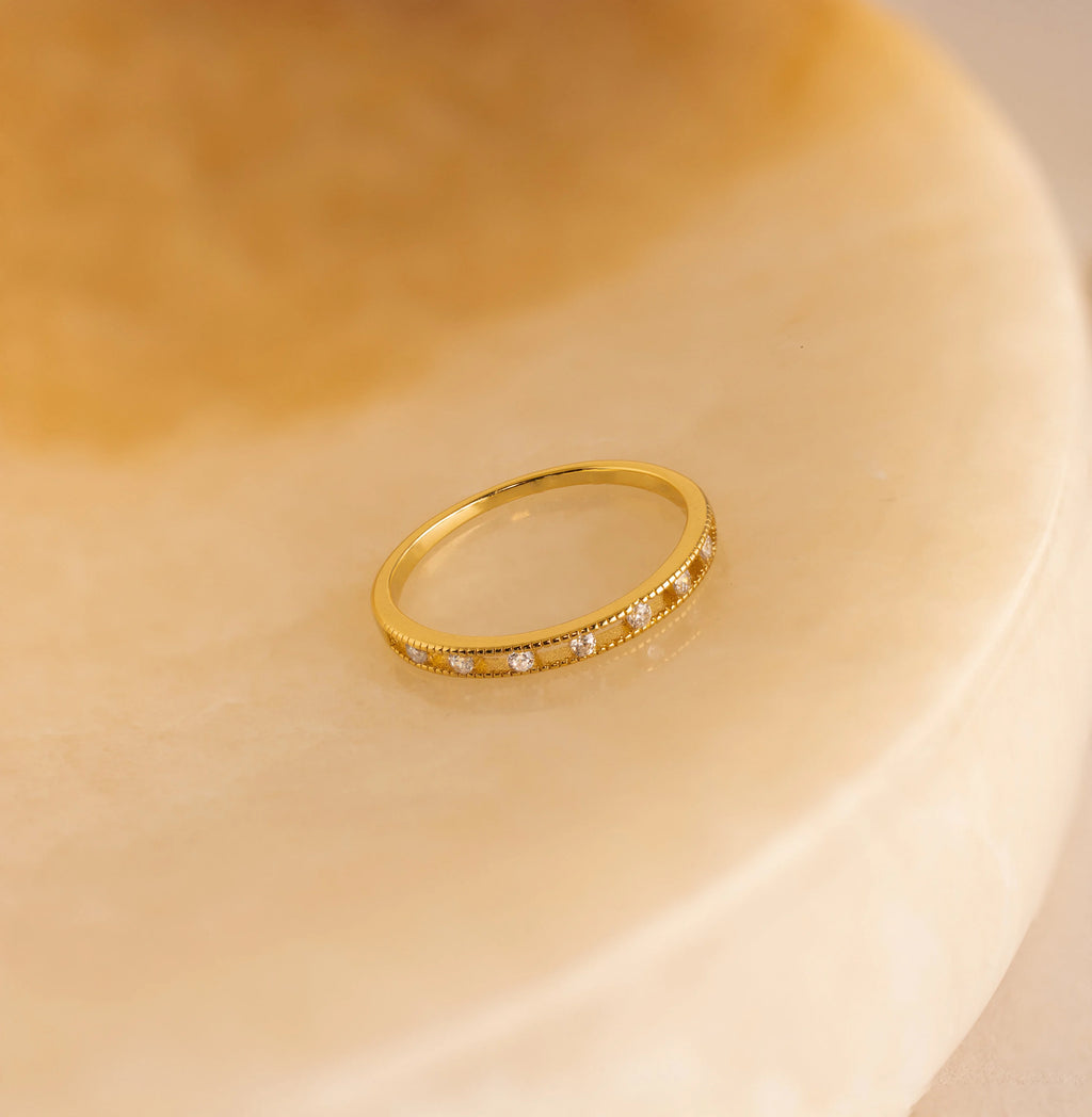 Diamond Station Ring featuring small diamonds displayed on a smooth, beige marble surface.