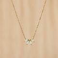 The White Opal Marquise Necklace features five marquise opal-like stones in a floral design, accented with gold and shown on a beige background.