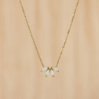 The White Opal Marquise Necklace features five marquise opal-like stones in a floral design, accented with gold and shown on a beige background.
