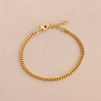 The Curb Chain Bracelet shines with minimal elegance, featuring a lobster clasp and extender chain for easy layering. Shown on a light beige background.