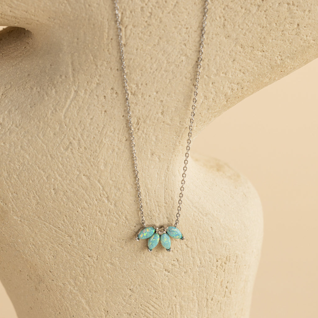Turquoise Opal Marquise Necklace featuring four small blue-green opal stones, elegantly displayed on a cream textured background.