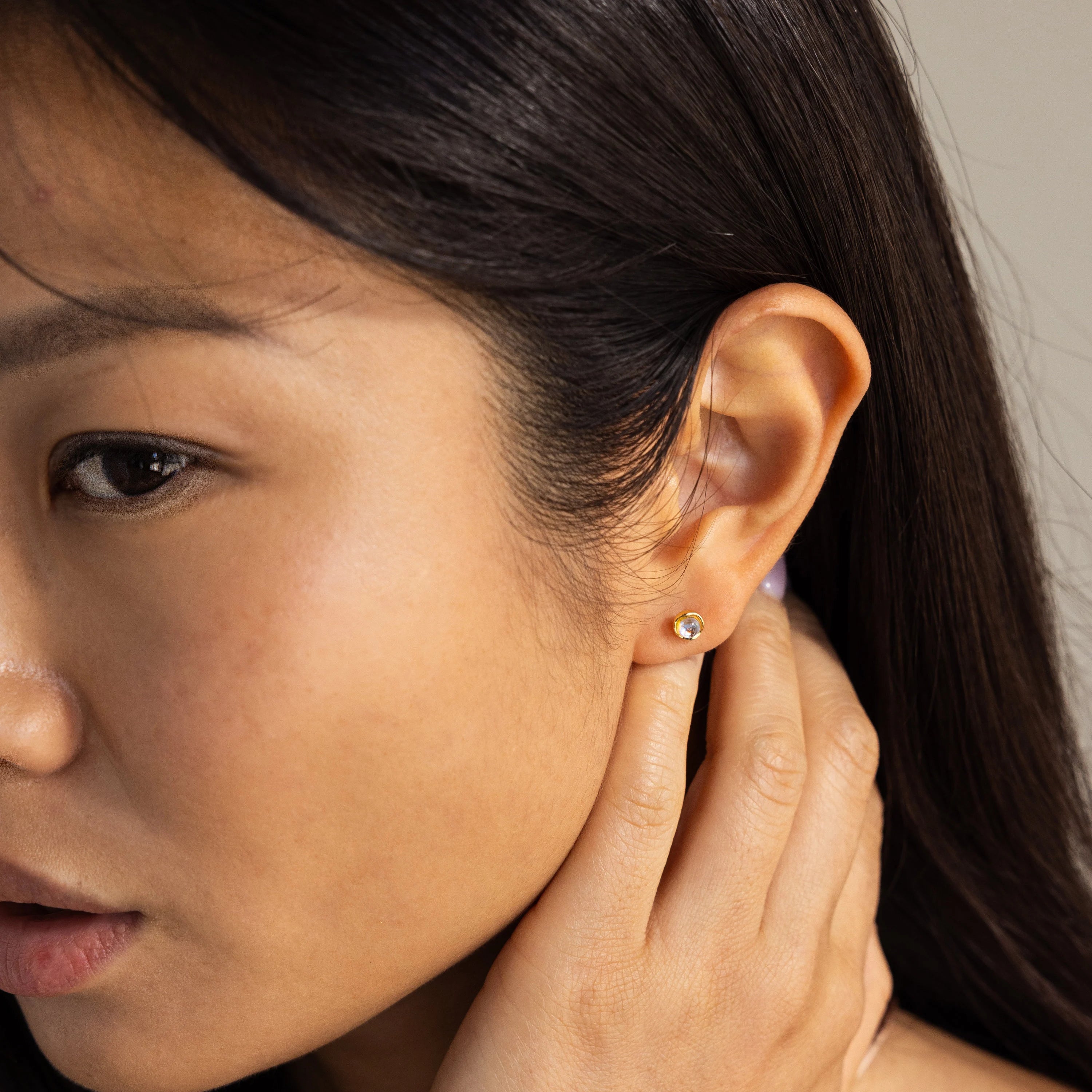 A close-up of a woman’s face showcases her Moonstone Studs, adding a touch of celestial charm to her look.