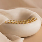 A row of gold rings, including the Marquise Bezel Birthstone Ring with colorful gemstones, displayed on a smooth white curved surface with fabric drapes.
