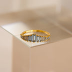The Art Deco Aquamarine Ring features rectangular, light blue gemstones and is displayed on a clear surface, radiating vintage glamour.