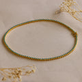 Gold anklet with turquoise stones, shown on a beige surface with dried flowers—pairs perfectly with our Turquoise Bezel Tennis Necklace for a coordinated look.