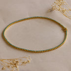 Gold anklet with turquoise stones, shown on a beige surface with dried flowers—pairs perfectly with our Turquoise Bezel Tennis Necklace for a coordinated look.