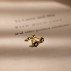 The Onyx Flower Studs sit on a softly lit, blurred text background, showcasing their elegant black onyx accents.