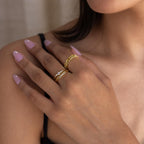 Close-up of a woman’s manicured hand wearing the Trio Diamond Stacking Ring Set and two gold rings, paired with a black strap top.