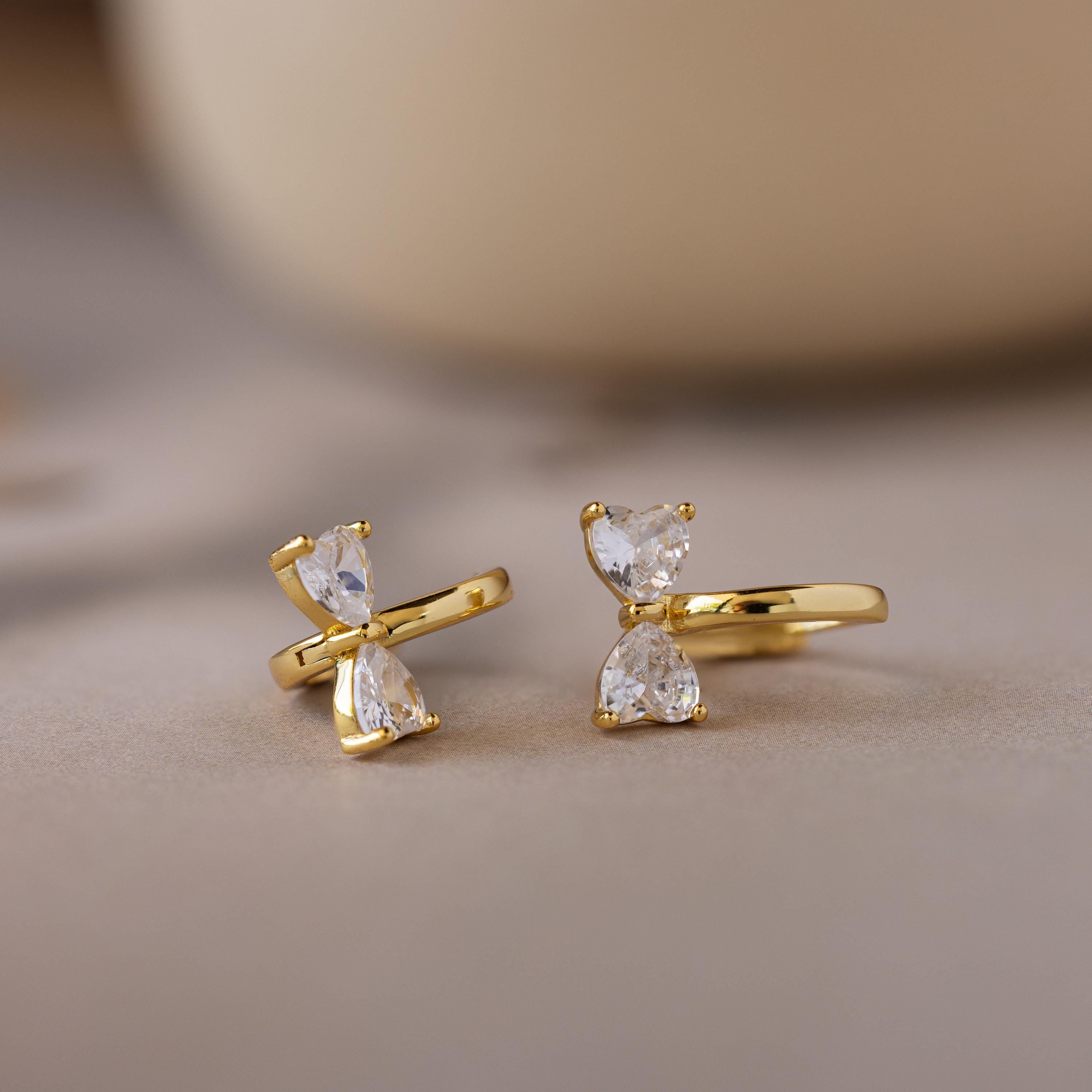 Diamond Bow Huggies featuring two clear, teardrop-shaped gems stacked vertically, displayed on a soft, neutral background.