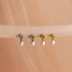 Two pairs of Love Knot Pearl Earrings—one silver, one gold—displayed on sheer beige fabric. Ideal as a wedding accessory or for anyone who loves vintage-inspired heart earrings.