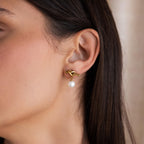 Close-up of a woman's ear wearing a Love Knot Pearl Earring with a dangling white pearl, perfect as an elegant wedding accessory.