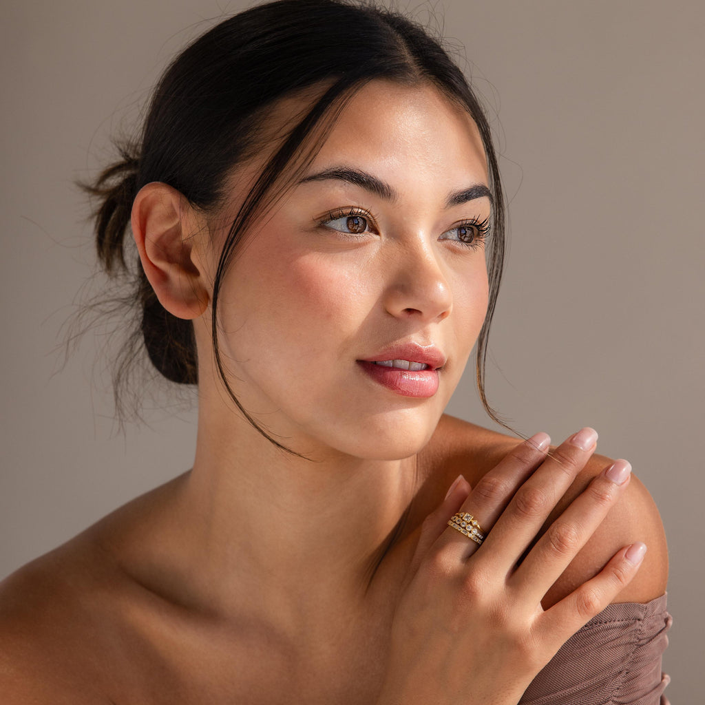 A woman with dark hair in a bun, wearing the Art Deco Diamond Ring Set, gazes softly to the side, exuding gentle elegance and vintage glamour.