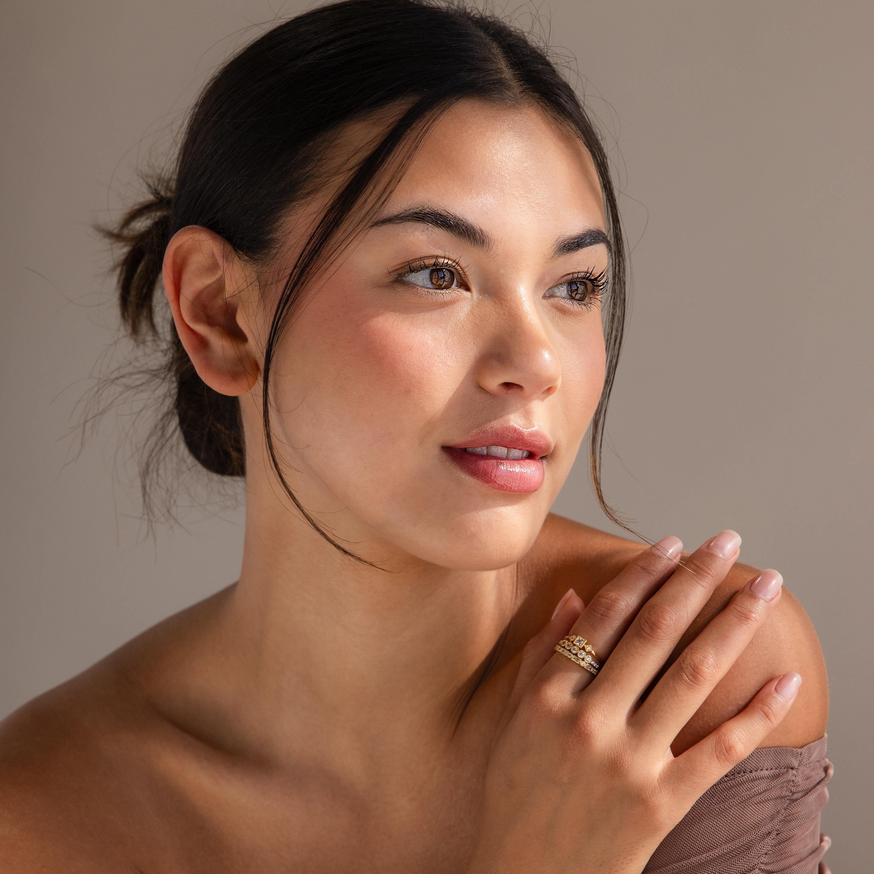 A woman with dark hair in a bun, wearing the Art Deco Diamond Ring Set, gazes softly to the side, exuding gentle elegance and vintage glamour.